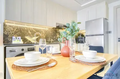 a kitchen with a wooden table with plates and glasses at Homely 1BR at Binghatti Avenue Al Jaddaf by Deluxe Holiday Homes in Dubai