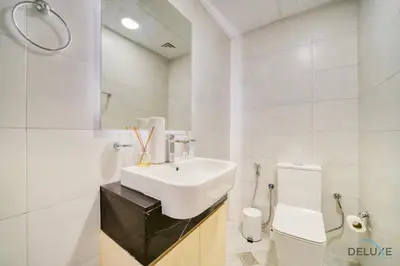 a white bathroom with a sink and a toilet at Homely 1BR at Binghatti Avenue Al Jaddaf by Deluxe Holiday Homes in Dubai
