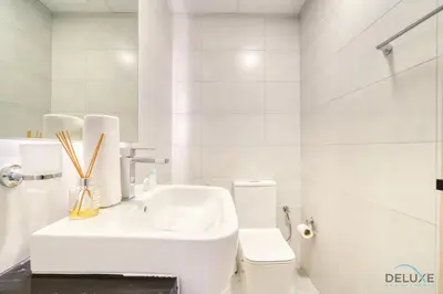 a white bathroom with a sink and a toilet at Homely 1BR at Binghatti Avenue Al Jaddaf by Deluxe Holiday Homes in Dubai