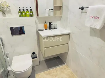 a white bathroom with a toilet and a sink at LV13 - Elegant Studio in Lake View Tower in Dubai
