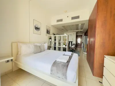 a bedroom with a large white bed and a bathroom at LV13 - Elegant Studio in Lake View Tower in Dubai