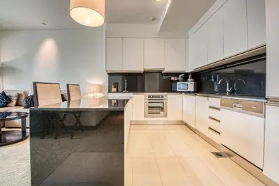 a kitchen with white cabinets and a black counter top at Graceful 1BR at The Address Residences Dubai Marina by Deluxe Holiday Homes in Dubai