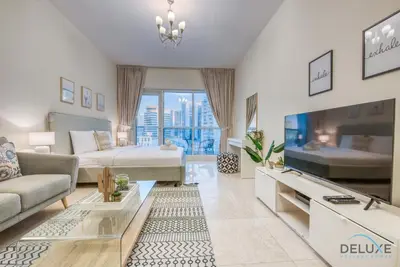 a large living room with a couch and a tv at Pleasant Studio at Safir Tower 1 Business Bay by Deluxe Holiday Homes in Dubai