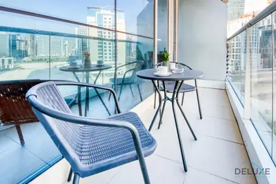 a balcony with two tables and chairs on a balcony at Pleasant Studio at Safir Tower 1 Business Bay by Deluxe Holiday Homes in Dubai