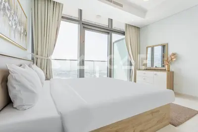 a bedroom with a large white bed and large windows at Staycae Holiday Homes - Paramount Midtown in Dubai