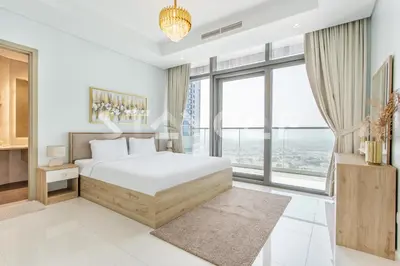 a white bedroom with a bed and a large window at Staycae Holiday Homes - Paramount Midtown in Dubai