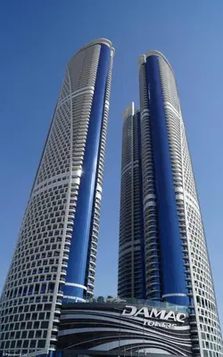 two tall skyscrapers in front of a blue sky at ALiving Elegant 1BR I Burj Khalifa View I Paramount Towers- 6103 in Dubai