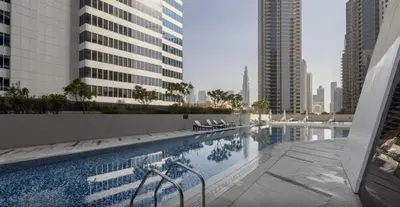 a swimming pool in a city with tall buildings at Stylish Studio with Burj Khalifa View in Dubai