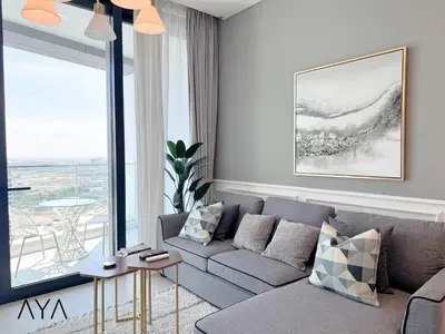 a living room with a couch and a large window at Jumeirah Gate Tower 1 - Stylish Apartment with Pool & City Views By ĀYA Boutique in Dubai