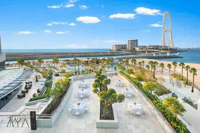a view of a beach with tables and palm trees at Jumeirah Gate Tower 1 - Stylish Apartment with Pool & City Views By ĀYA Boutique in Dubai