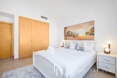 a bedroom with a white bed and a painting on the wall at LUX - The Shoreline Penthouse Suite in Dubai