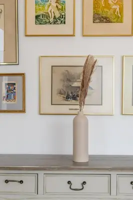 a vase on top of a dresser with pictures on the wall at GuestReady - Upscale Modern Apt in Downtown in Dubai