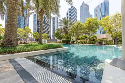 a swimming pool with palm trees and buildings at GuestReady - Upscale Modern Apt in Downtown in Dubai
