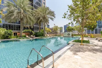 an empty swimming pool with palm trees and buildings at GuestReady - Upscale Modern Apt in Downtown in Dubai