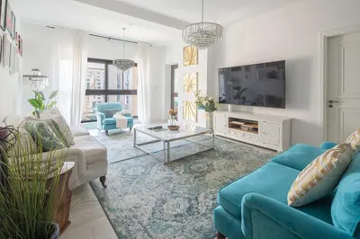a living room with a blue couch and a tv at Frank Porter - Fairmont Residence South in Dubai