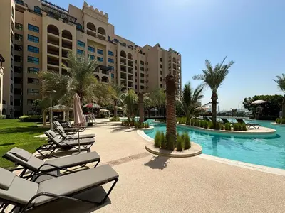 a resort pool with lounge chairs and a resort at Frank Porter - Fairmont Residence South in Dubai