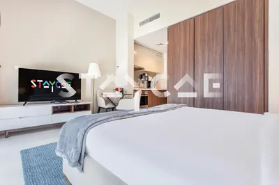 a bedroom with a white bed and a tv at Staycae Holiday Homes - Vera by DAMAC Near Downtown, Business Bay in Dubai