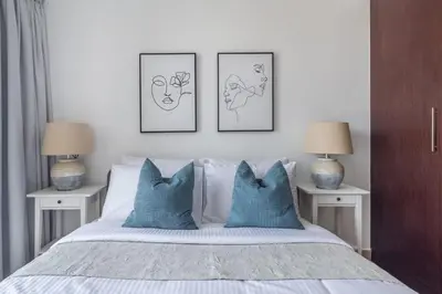 a bed with blue pillows and three pictures on the wall at Frank Porter - Icon Tower 1 in Dubai