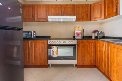 a kitchen with wooden cabinets and a stove top oven at Frank Porter - Icon Tower 1 in Dubai