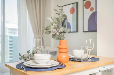 a dining room table with plates and a vase with a plant at Distinguished 1BR at Vera Tower Business Bay by Deluxe Holiday Homes in Dubai