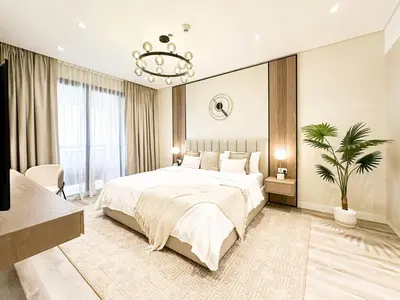 a bedroom with a large bed and a chandelier at Relaxing 1 bedroom apartment at 5 Star Resort in Dubai