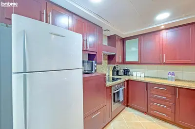 a kitchen with red cabinets and a white refrigerator at bnbmehomes - Túria Tower A in Dubai