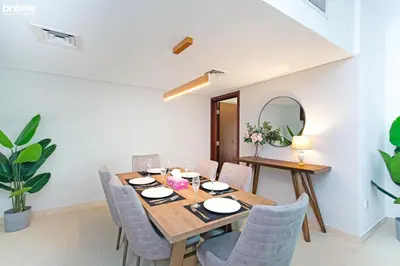 a dining room with a table and chairs and a mirror at bnbmehomes - Túria Tower A in Dubai