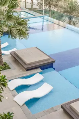 a swimming pool with white chairs on the ground at GuestReady - Deluxe Waterfront View in the Marina in Dubai