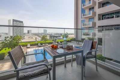 a balcony with a table and chairs and a pool at Frank Porter - Azizi Aura in Dubai