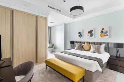 a bedroom with a large bed and a yellow bench at ALiving Luxe 2BR with higest Infinity Pool Close to Dubai Mall & Burj Khalifa in Dubai