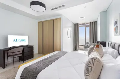 a white bedroom with a bed and a tv at ALiving Luxe 2BR with higest Infinity Pool Close to Dubai Mall & Burj Khalifa in Dubai