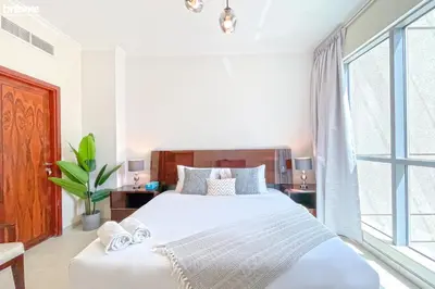 a bedroom with a white bed and a large window at bnbme - Luxury 2BR Near Burj Khalifa Apt Balcony Pool Gym Concierge Near Dubai Mall in Dubai