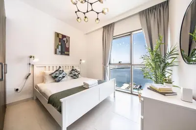 a white bedroom with a bed and a large window at Panoramic Burj Views - Lovely 3BR in Creek Harbour in Dubai