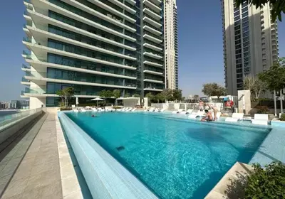 a swimming pool in front of a large building at Lovely 1 BD apartment in Beach Vista Tower in Dubai