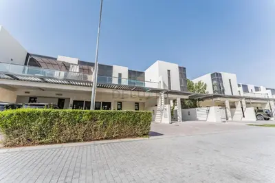 a building with a hedge in front of it at Flawless 3BR Townhouse with Assistant's Room at DAMAC Hills 2 by Deluxe Holiday Homes in Dubai