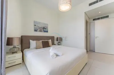 a white bedroom with a large bed and a lamp at Flawless 3BR Townhouse with Assistant's Room at DAMAC Hills 2 by Deluxe Holiday Homes in Dubai