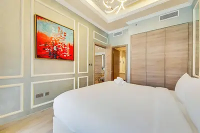 a bedroom with a white bed and a painting on the wall at Studio One - Beautiful One Bedroom in Dubai