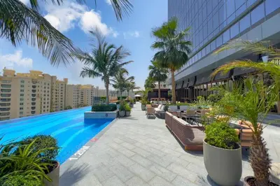 a swimming pool with palm trees and a building at FAM Living - Palm Tower - Palm Jumeirah - Panoramic Studios in Dubai