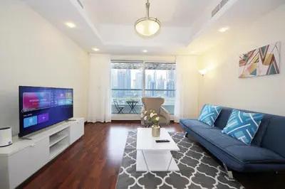 a living room with a blue couch and a tv at RH- Lovely 1BR apartment in JLT, near metro in Dubai