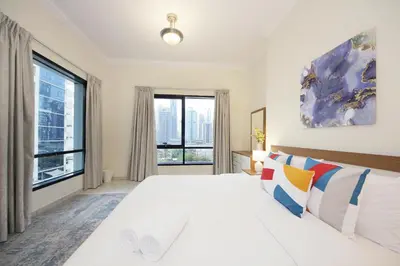 a white bedroom with a large bed and large windows at RH- Lovely 1BR apartment in JLT, near metro in Dubai