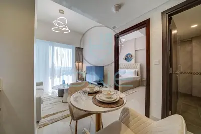 a living room with a table and a bedroom at Elegant 1BR with Sofa Bed Close to Metro in Dubai