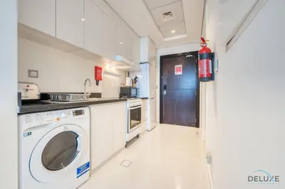 a kitchen with a washer and dryer in a room at Intimate Studio in Damac Ghalia Jumeirah Village Circle by Deluxe Holiday Homes in Dubai