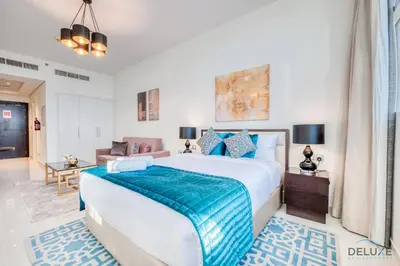 a bedroom with a large bed with a blue blanket at Intimate Studio in Damac Ghalia Jumeirah Village Circle by Deluxe Holiday Homes in Dubai