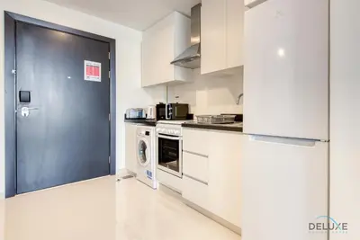 a kitchen with white cabinets and a black door at Peaceful Studio at Celestia A Dubai South by Deluxe Holiday Homes in Dubai