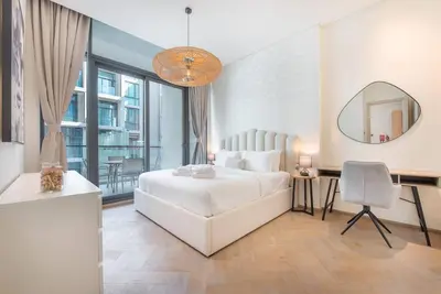 a white bedroom with a large bed and a mirror at Modern flat with KING SIZE bed and HIGH SPEED Wifi in Dubai