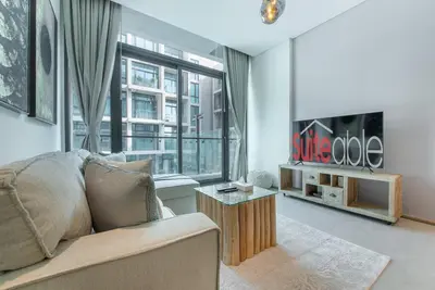 a living room with a couch and a large window at Modern flat with KING SIZE bed and HIGH SPEED Wifi in Dubai