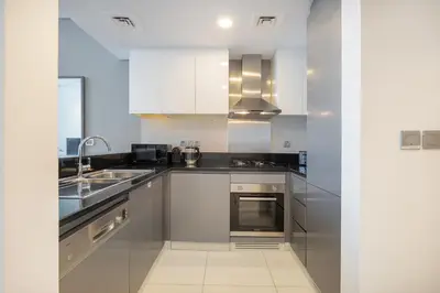 a kitchen with stainless steel appliances and white cabinets at Spectacular Burj Khalifa view service apartment in Dubai