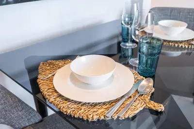a table with two white bowls and plates on a table at Spectacular Burj Khalifa view service apartment in Dubai