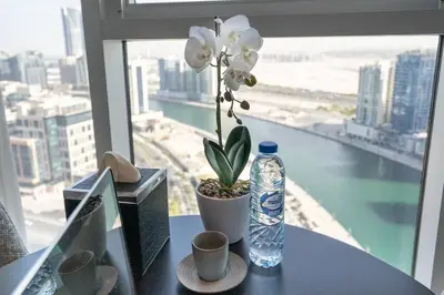 a bottle of water and a flower on a table with a window at At The Top Burj View STUDIO - Special offer in Dubai