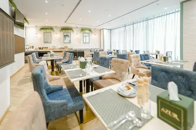 a restaurant with blue chairs and tables in a room at Azur Regency Hotel Apartments in Dubai